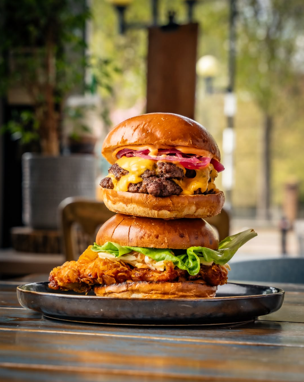 Smashed cheeseburger stacked on a cornflake chicken burger at Cristina's Cafe Romford